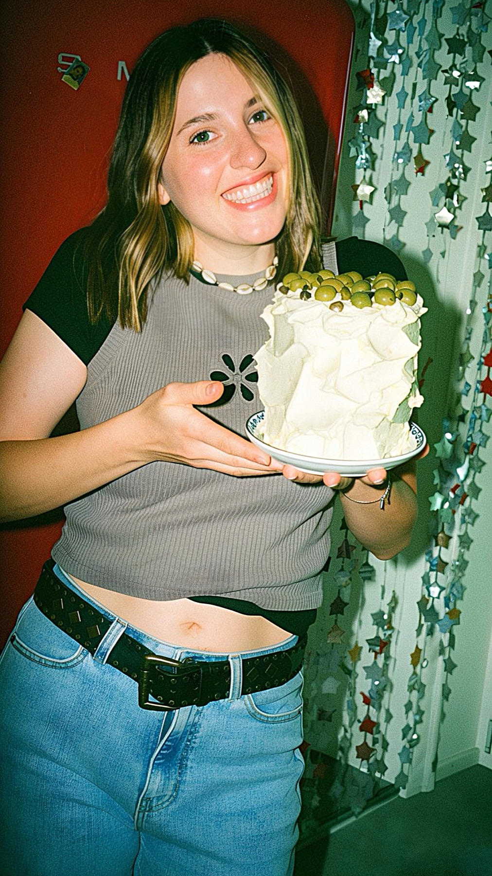 Sarah Pechinger von ZIG Food lacht und hält eine weiße Torte mit grünen Oliven in der Hand