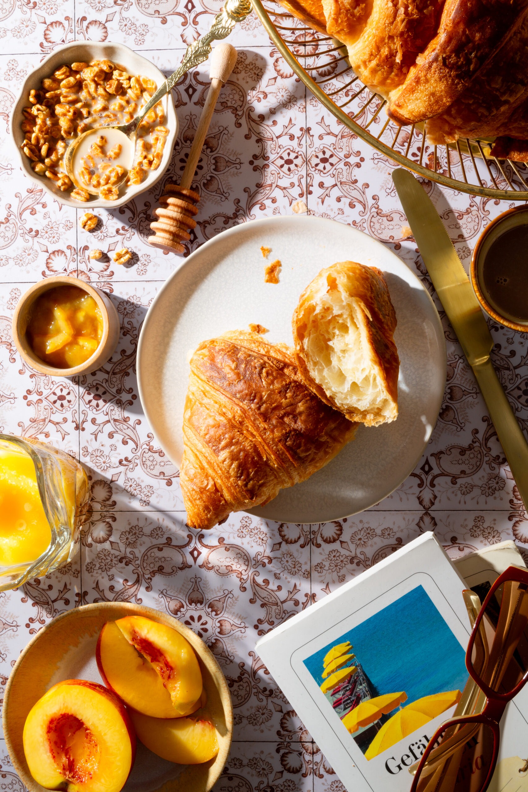 Ein Frühstück mit italienischem Flair, mit Croissant, Orangenmarmelade, Cereals, einem saftigen Pfirsich und frischem Orangensaft.